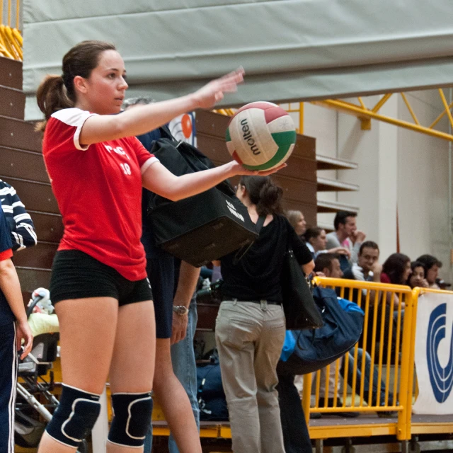 two girls play volley ball in a large sports court