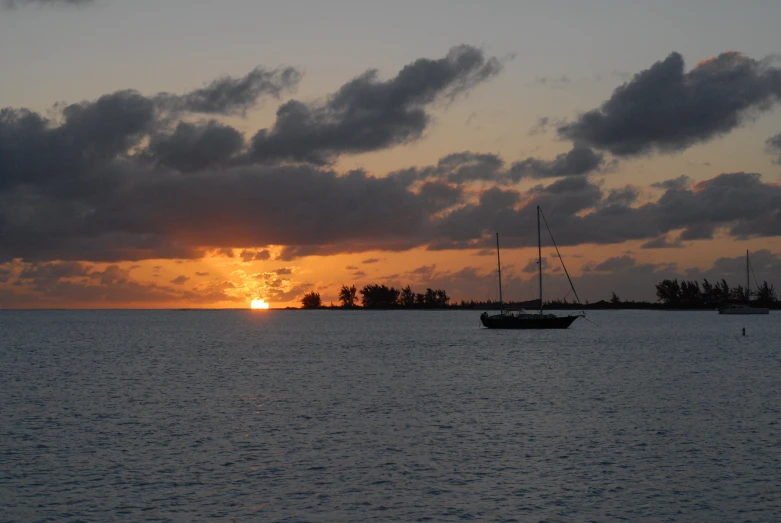 a boat floating in the ocean near a sunset