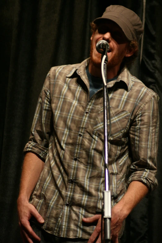 a man wearing a brown hat holding a microphone in his hands