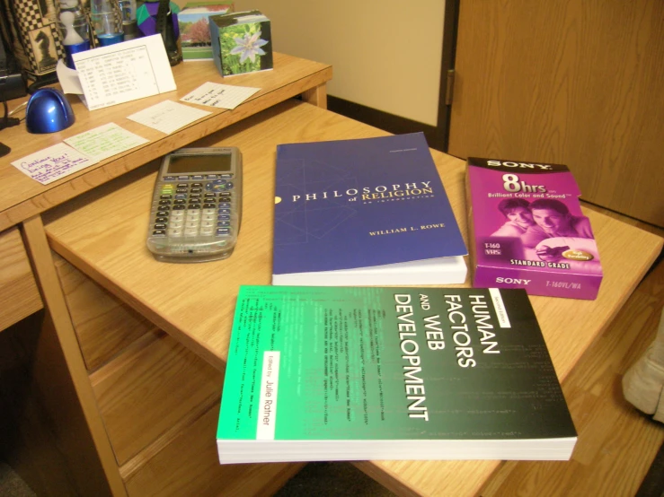 some books sitting on a desk with a calculator and cell phone