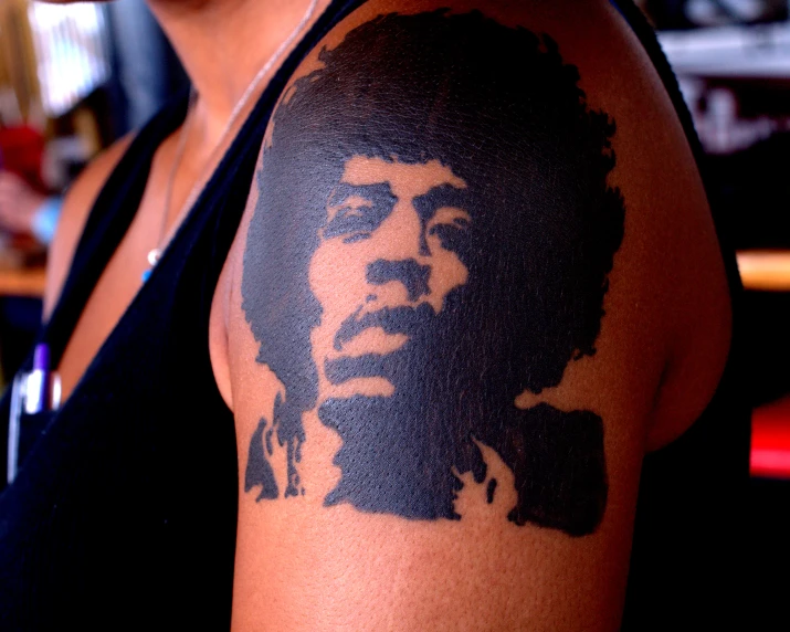 a close up of a woman's arm with the face of a man with an afro
