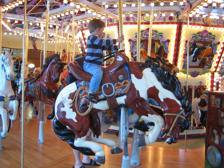 a small boy riding a merry go round at a merry go round