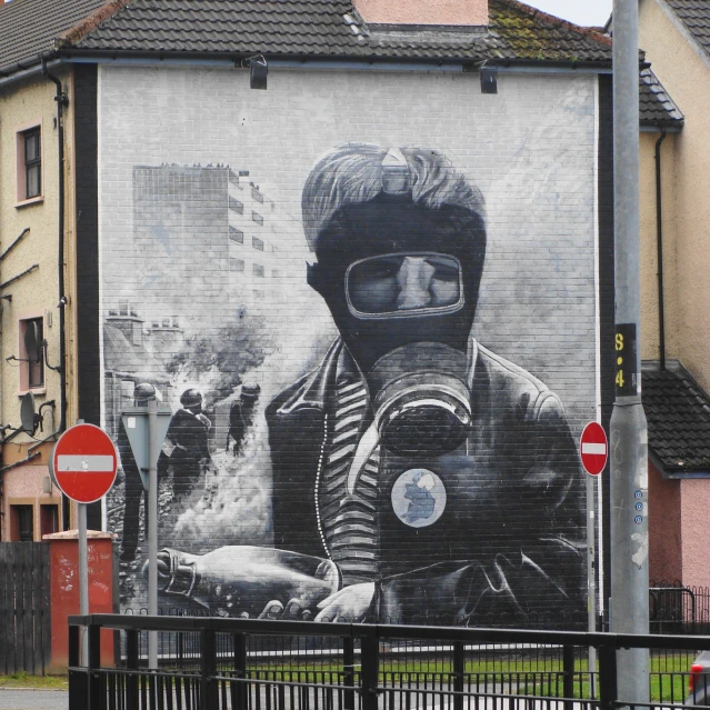 a man wearing glasses and riding a motor cycle in front of a wall mural