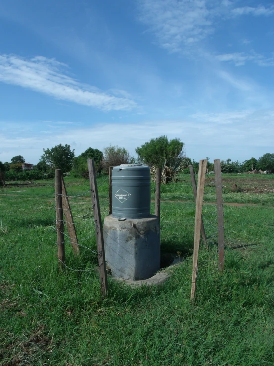 large gray barrel standing in the middle of some green field