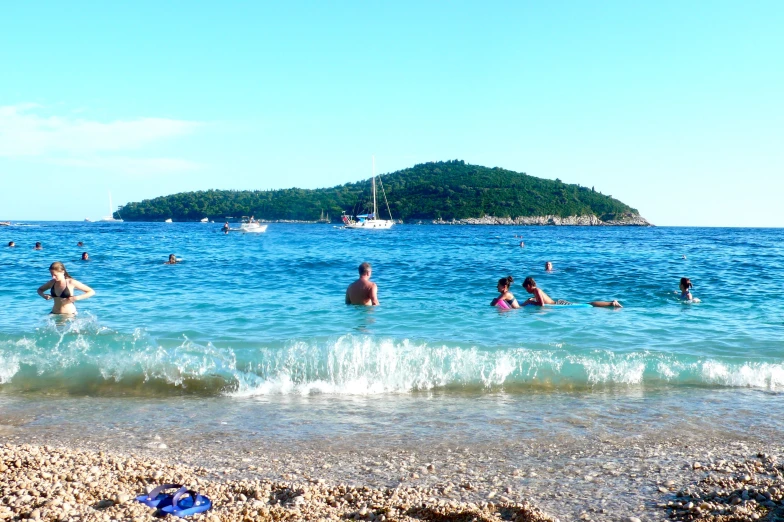 people swimming in the ocean with a little island in the background