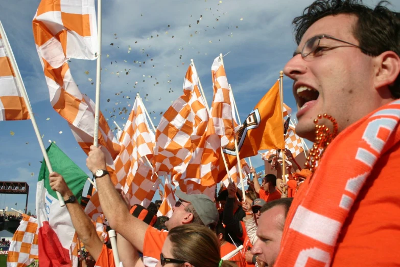 a crowd of people waving orange and white flags