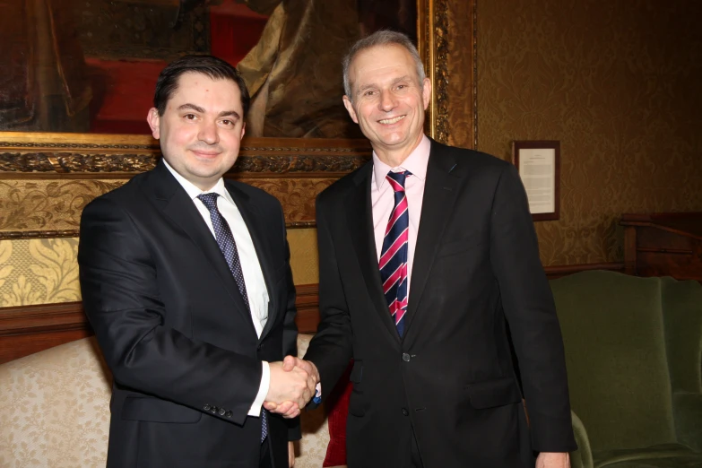 a couple of men standing next to each other in front of a painting