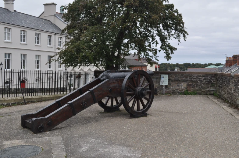 the cannon is near a building near a tree