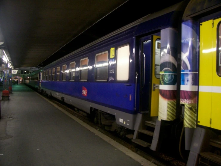 a purple and yellow train at the station