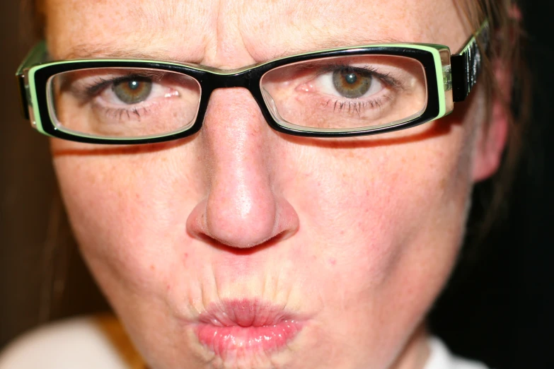 a close up image of a woman wearing glasses and pulling on some lipstick