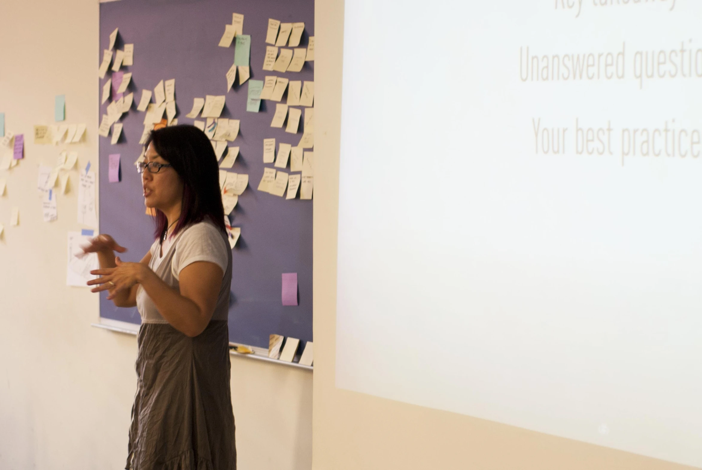 woman speaking in front of a projector screen