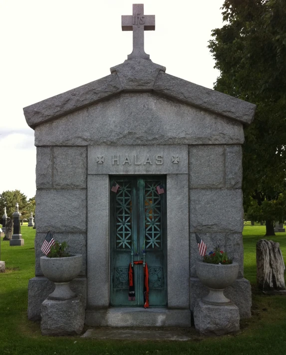 a small gray cemetery building with the doors open