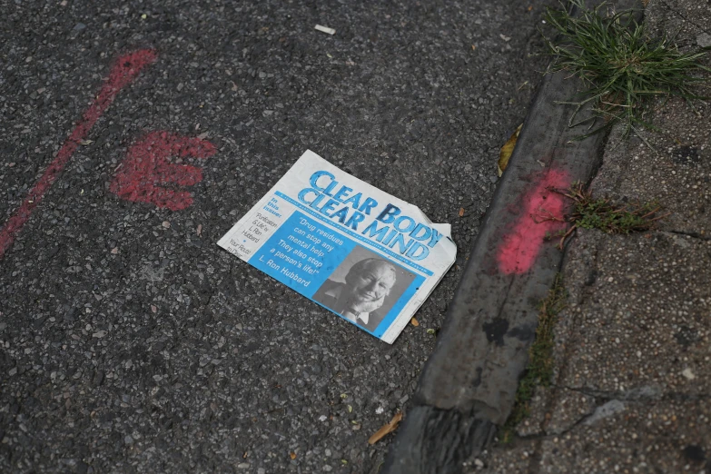a newspaper lying on the ground near the curb