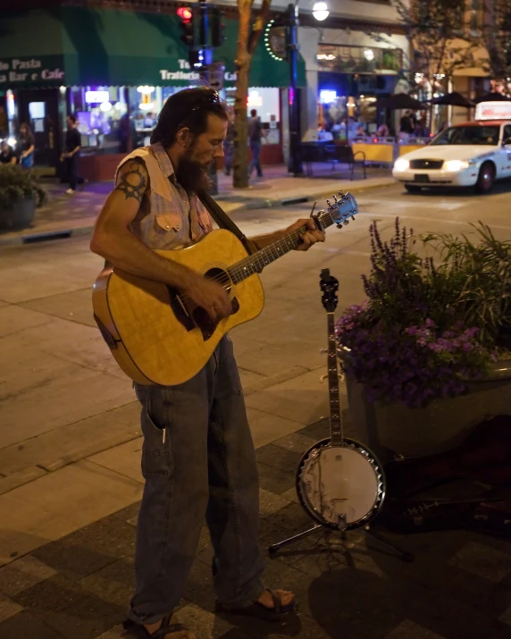 a man holding a guitar on the side of the road