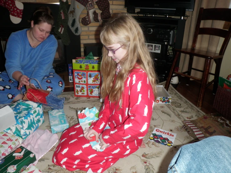 there are two s opening gifts in front of a fireplace