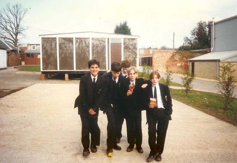 three boys in suits and one boy is drinking a drink