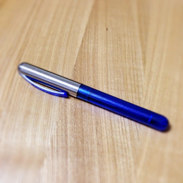 a metal pen resting on top of a wooden table