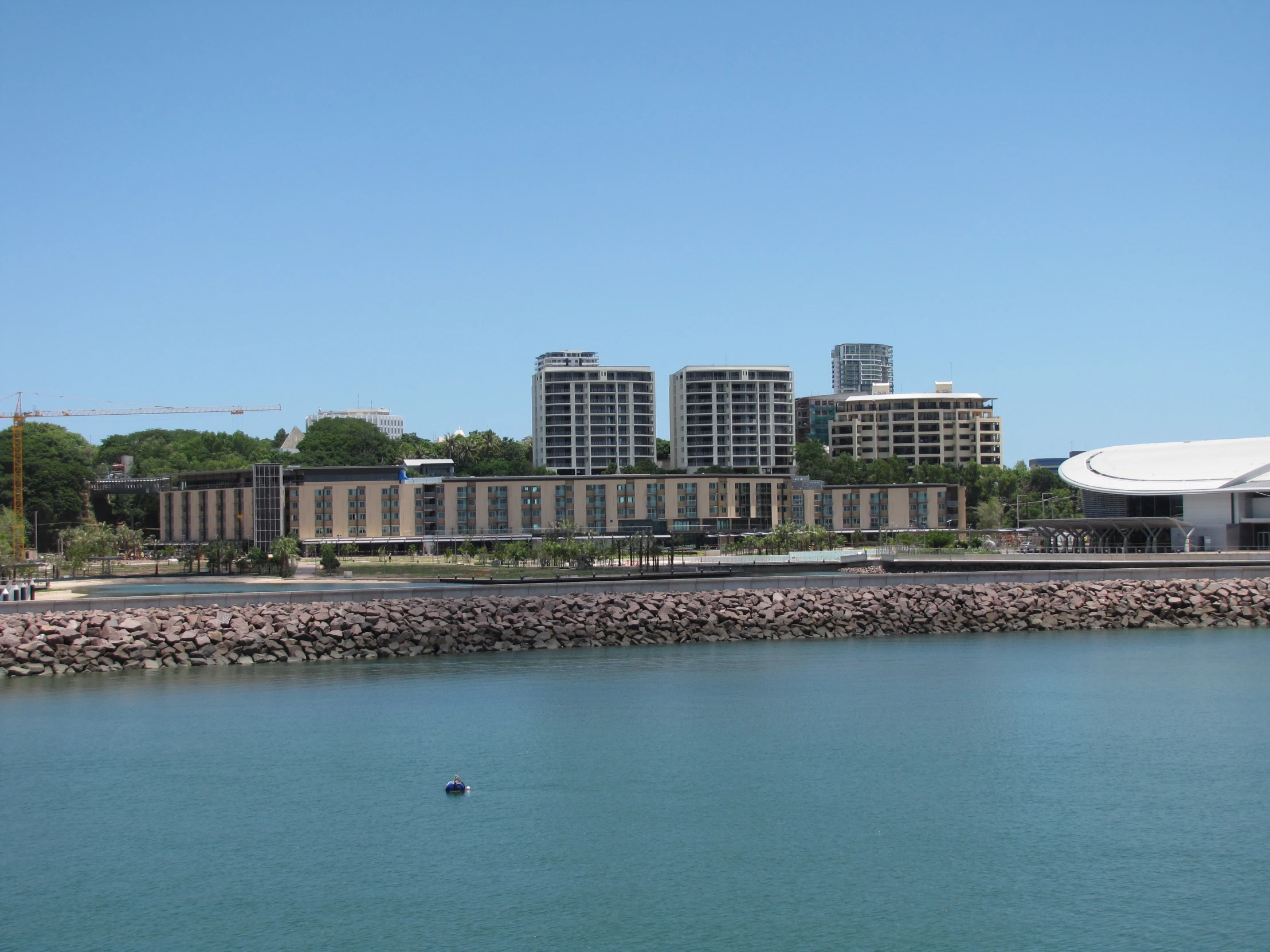 a blue body of water with a row of tall buildings and trees