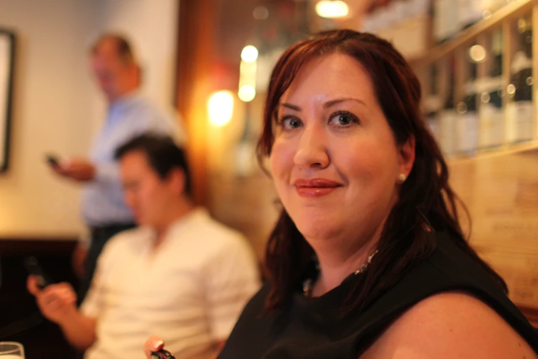 a woman smiling while holding a slice of pizza