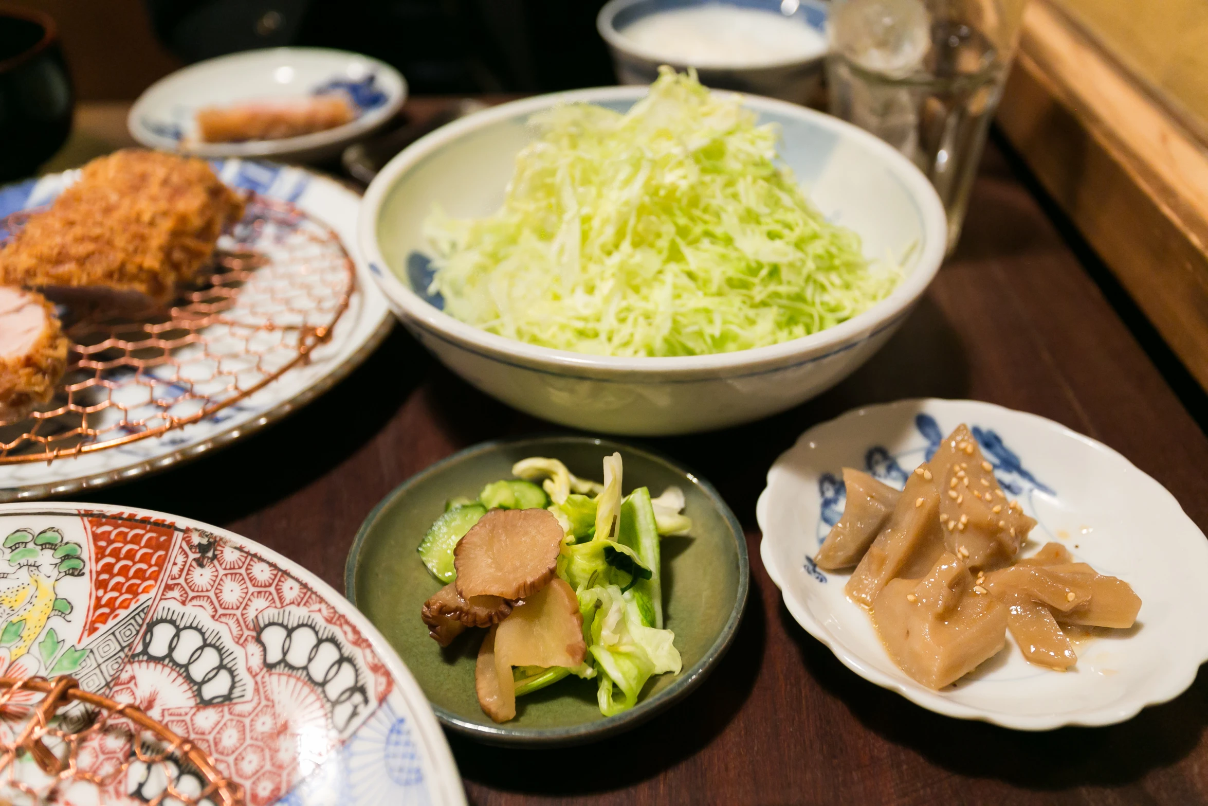 a table with many plates of food that include vegetables