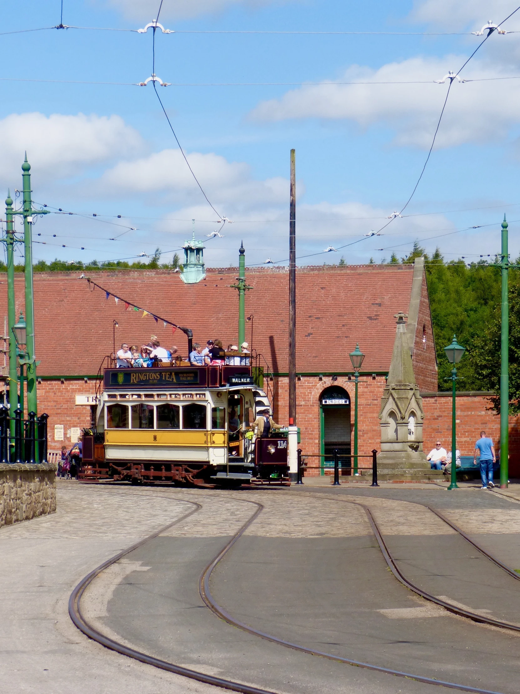 a tram with people on the top of it is passing by an abandoned building