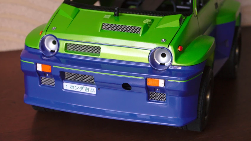 a small plastic toy car with eyes and a hood