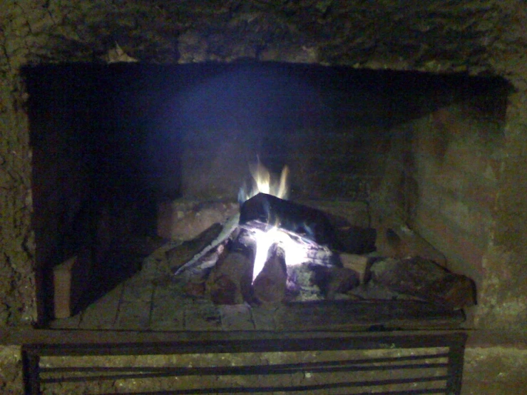 a brick fire burning inside of a stone fireplace