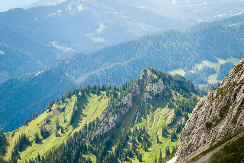 a mountain range covered in green forest on a sunny day