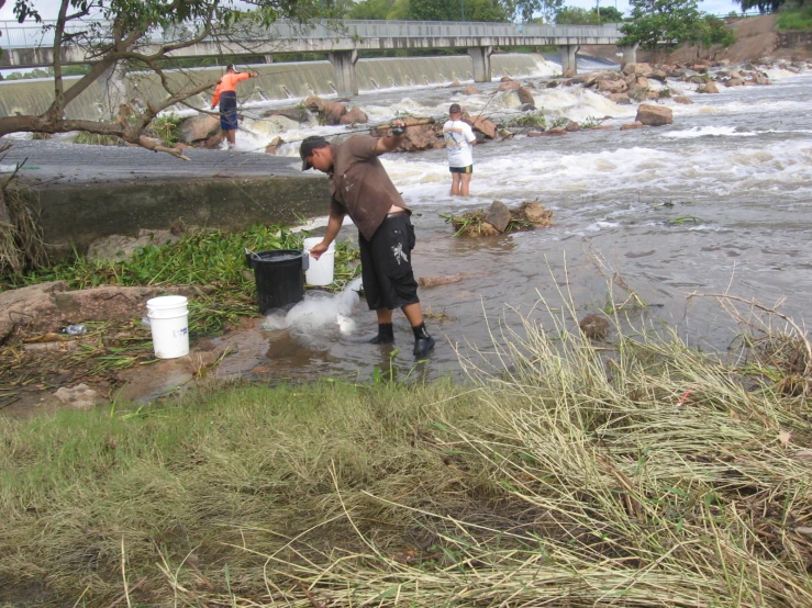 a man standing on top of a river next to a bucket