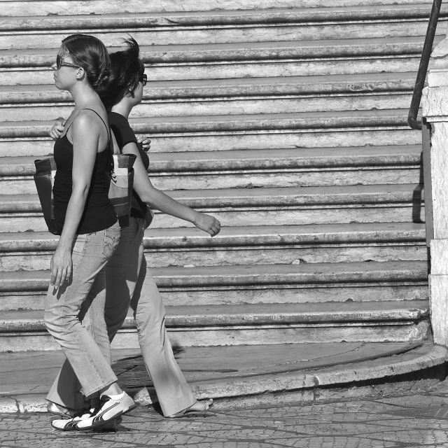 two young women walking down the sidewalk next to some steps