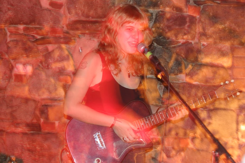 a woman singing on stage next to a guitar