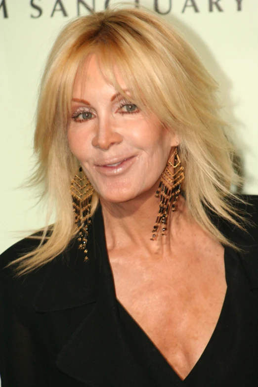 a blonde woman is smiling and has earrings on