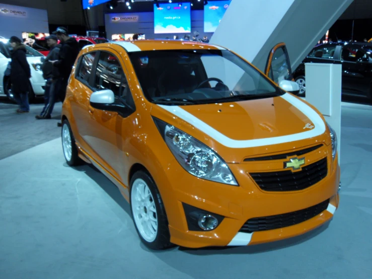 an orange and white chevrolet cer vehicle parked in a showroom