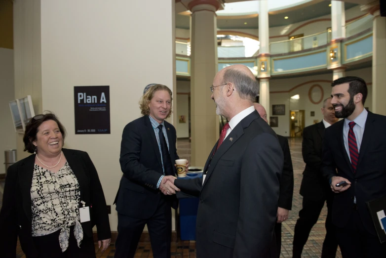 two men are talking with some women in suits