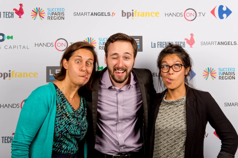 three people pose for a po on the red carpet