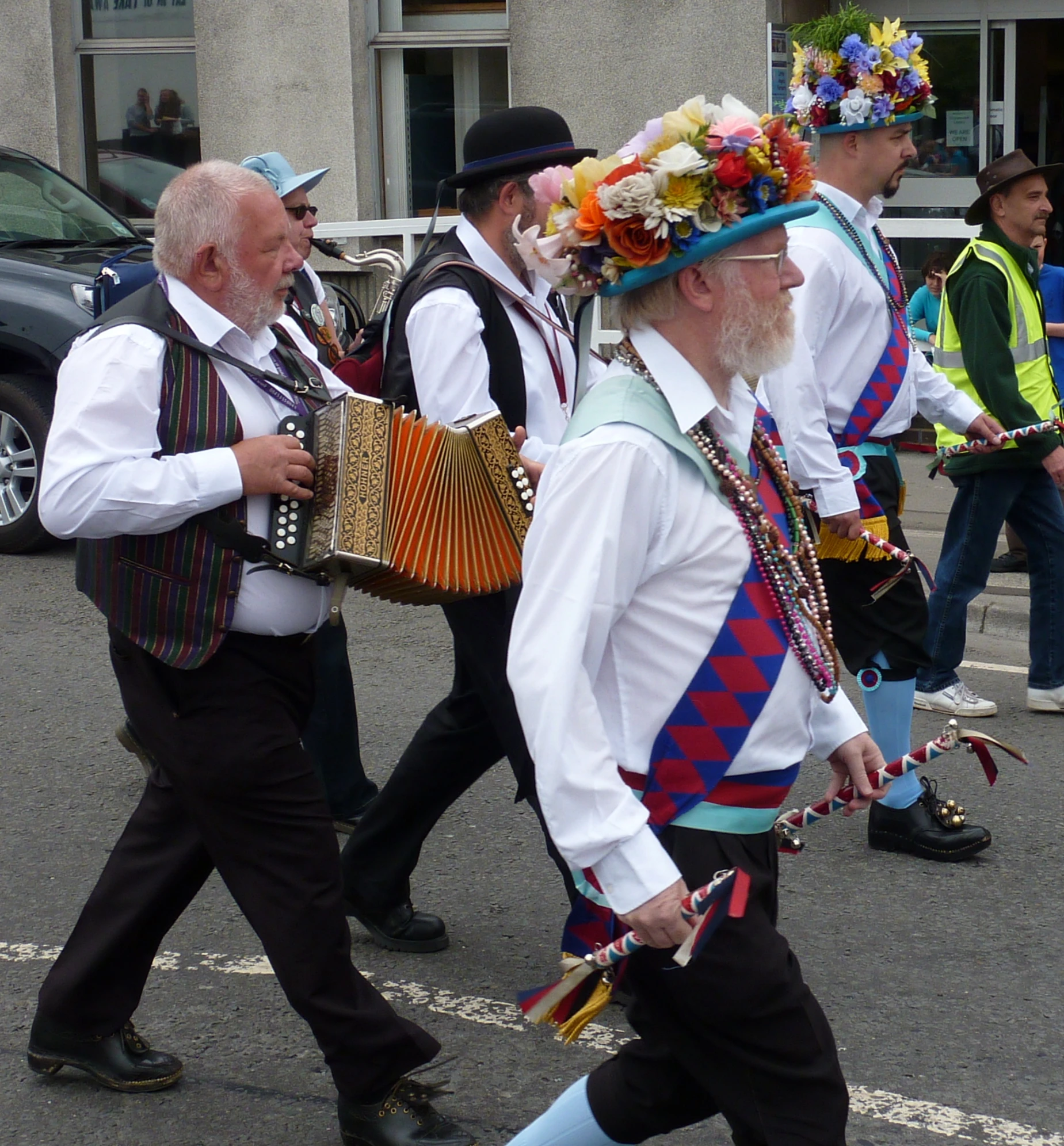 an old man walking down the road with some accordions and wearing some costumes