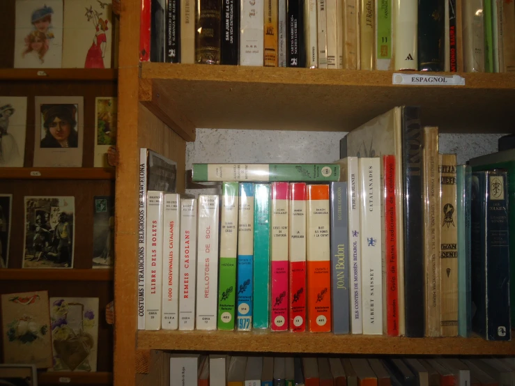 a wooden book case filled with books next to a bunch of pictures