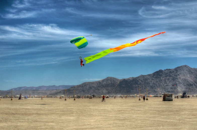 some people are flying kites in the middle of an arid area