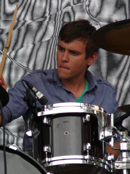 a young man playing the drums in front of a microphone