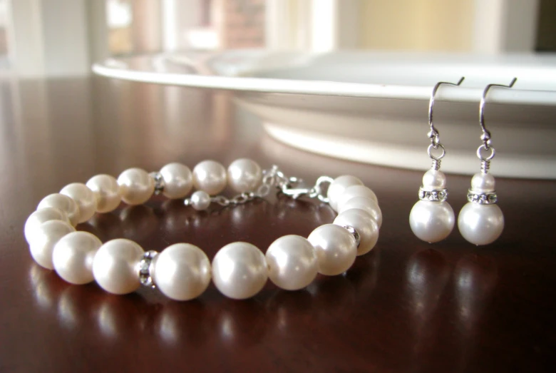 a white necklace, pair of earrings and a celet with pearls