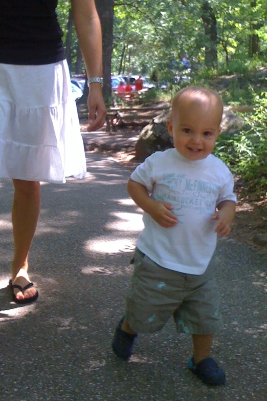 the baby is walking on the path in the woods