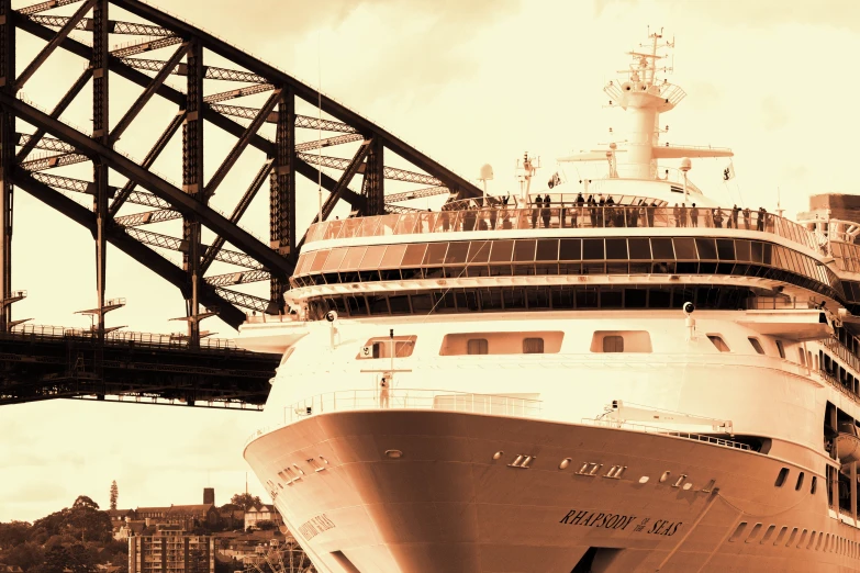 a large white cruise ship is sailing under a bridge