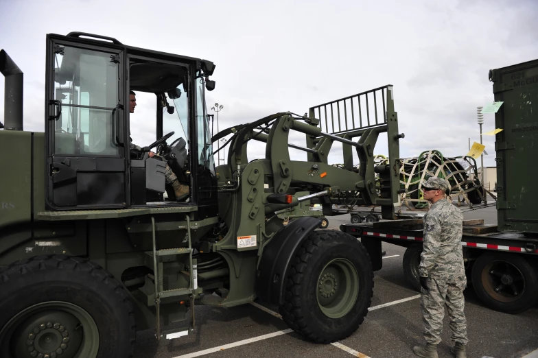 military man stands in front of a large truck