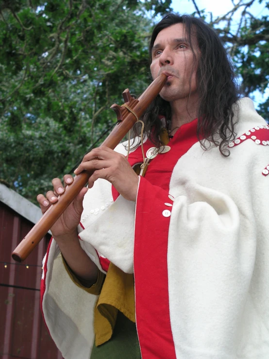 a man playing a flute near trees