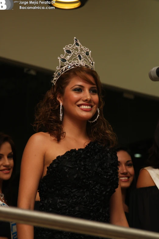 a smiling young lady in a black dress and a tiara