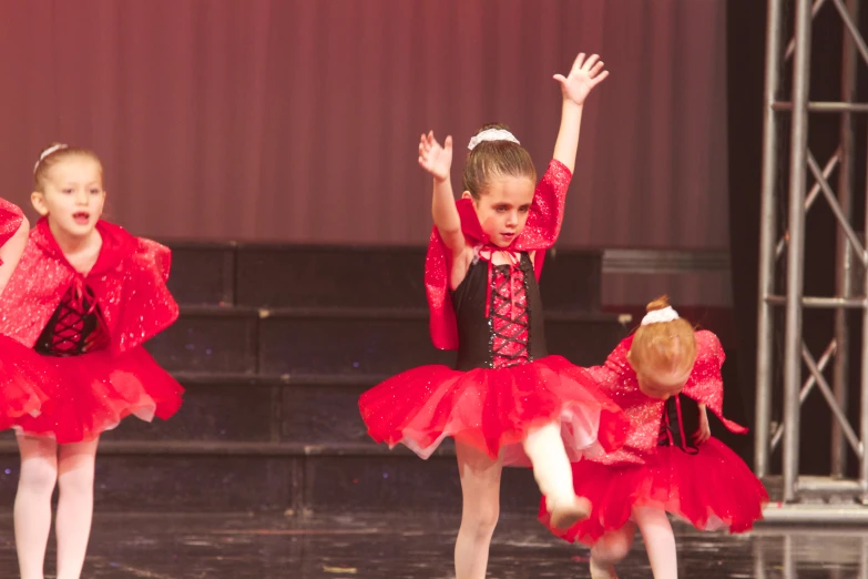 little girls in red dresses doing exercises on stage