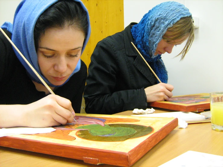 two girls doing artwork at a table together