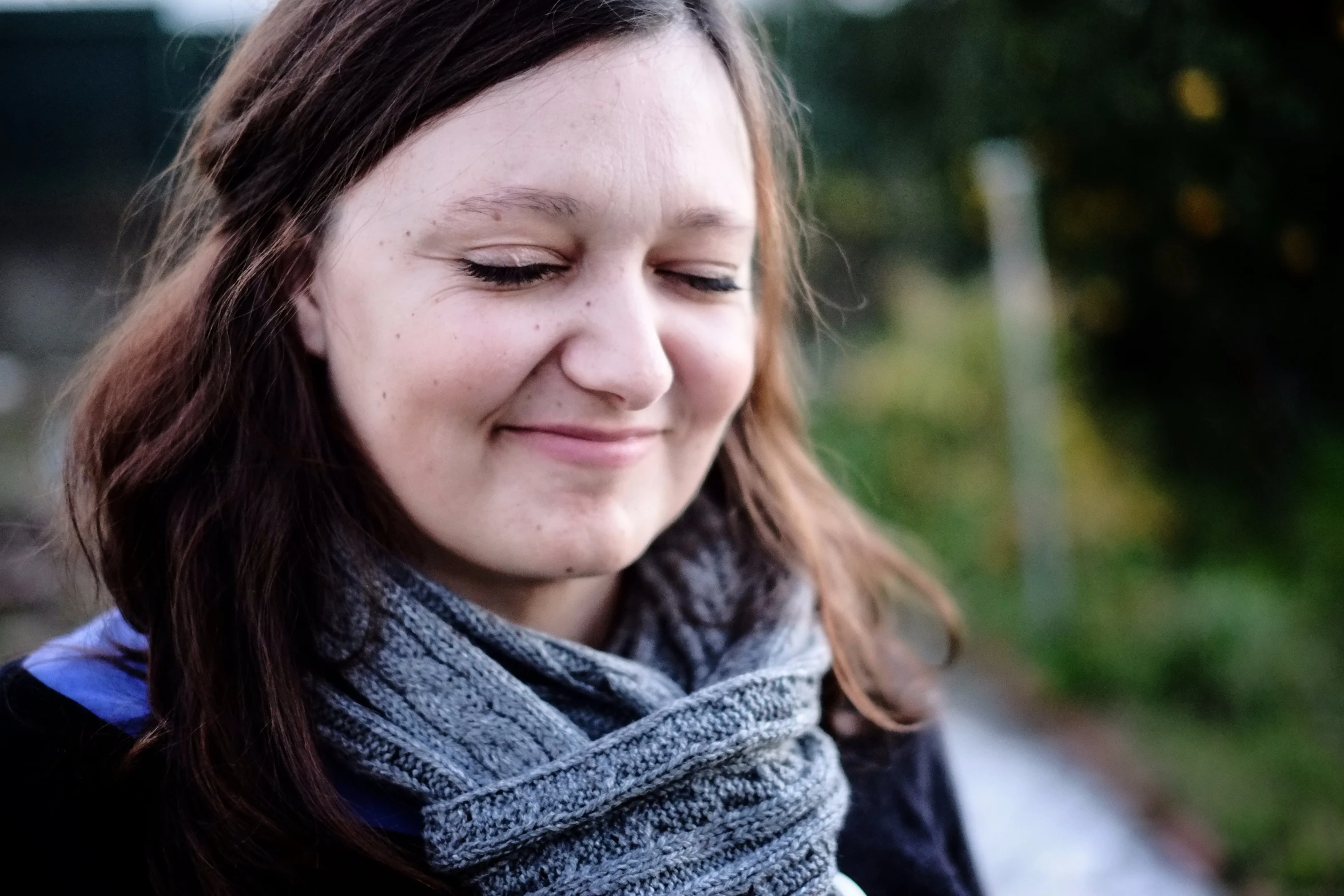 a woman standing outside smiles while looking at her phone