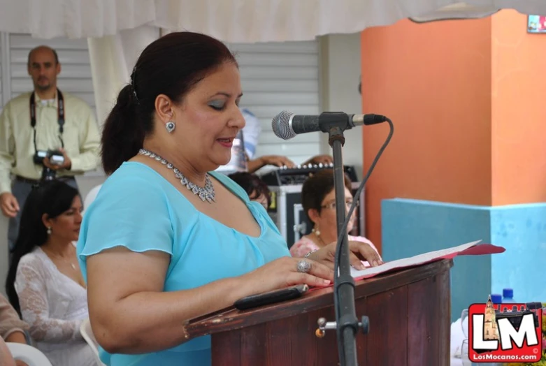 the woman in blue shirt is speaking into a microphone