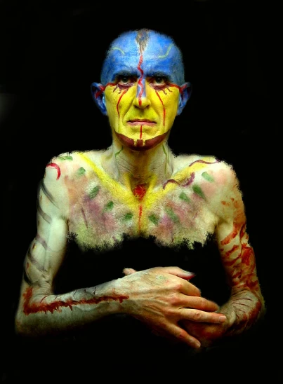 a man with multi - colored painted on his body, arms and chest